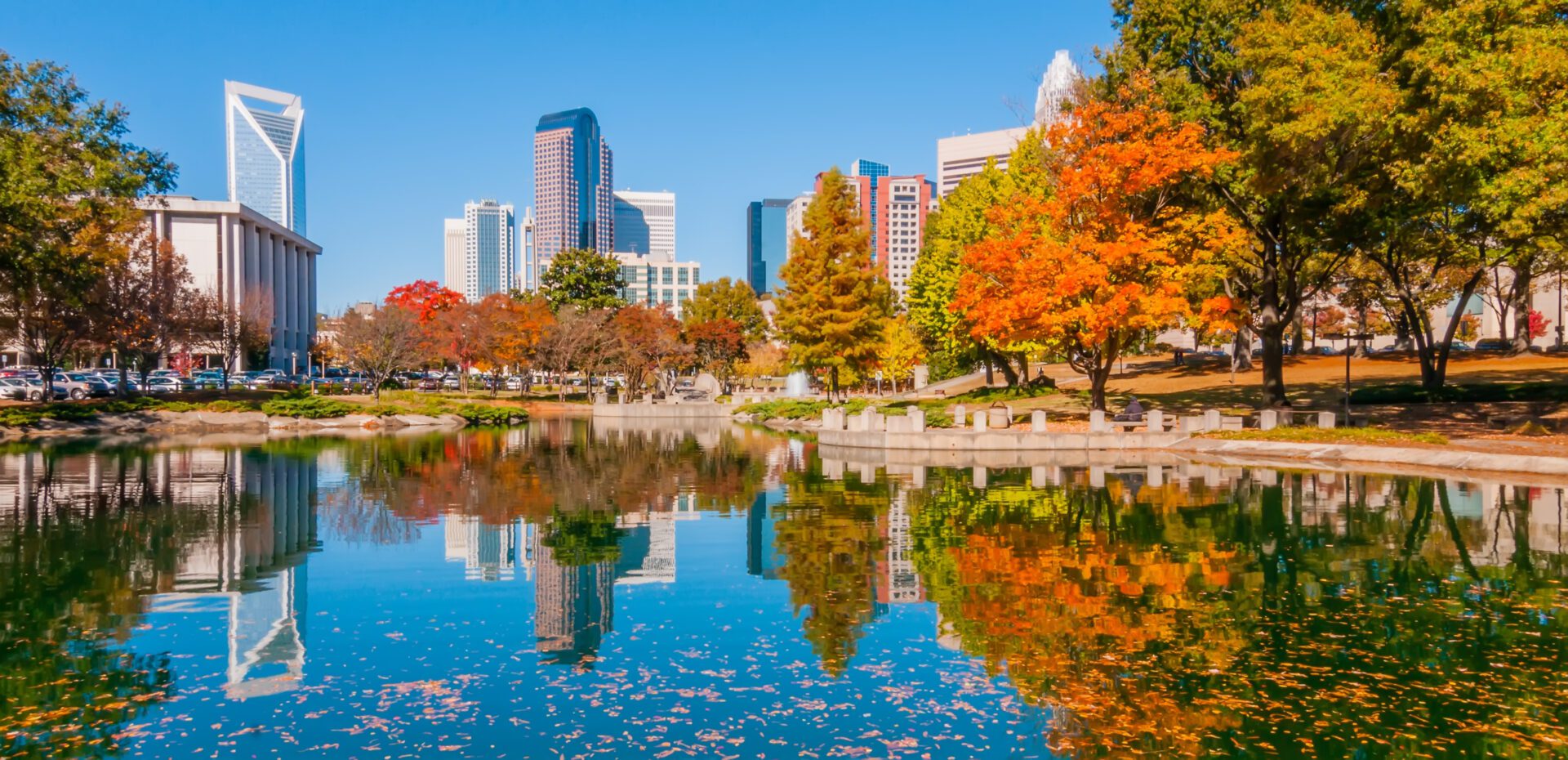 Downtown towers mirrored on pond with fall foliage